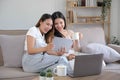 Two happy Asian women best friends in casual wear laughing while working with tablet at home in living room Royalty Free Stock Photo