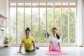 Two happy asian women in yoga poses in yoga studio with natura llight setting scene / exercise concept / yoga practice / copy