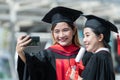 Two happy Asian young beautiful graduate female students with University degree standing and holding diploma taking selfie picture Royalty Free Stock Photo