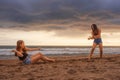 Two happy and attractive young Asian Chinese women girlfriends or sisters having fun playing with sand on sunset beach in beautifu Royalty Free Stock Photo