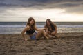 Two happy and attractive young Asian Chinese women girlfriends or sisters having fun playing with sand on sunset beach in beautifu Royalty Free Stock Photo