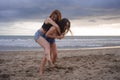 Two happy and attractive young Asian Chinese women girlfriends or sisters having fun playing in the sand on sunset beach in beauti Royalty Free Stock Photo