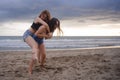 Two happy and attractive young Asian Chinese women girlfriends or sisters having fun playing in the sand on sunset beach in beauti Royalty Free Stock Photo