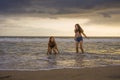 Two happy and attractive young Asian Chinese women girlfriends or sisters having fun playing in the sea on sunset beach in beautif Royalty Free Stock Photo