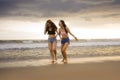 Two happy and attractive young Asian Chinese women girlfriends or sisters having fun walking on the beach laughing and talking bea Royalty Free Stock Photo