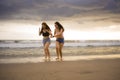 Two happy and attractive young Asian Chinese women girlfriends or sisters having fun walking on the beach laughing and talking bea Royalty Free Stock Photo