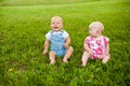 Two happy baby boy and a girl age 9 months old, sitting on the grass and interact, talk, look at each other. Royalty Free Stock Photo