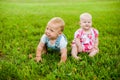 Two happy baby boy and a girl age 9 months old, sitting on the grass and interact, talk, look at each other. Royalty Free Stock Photo