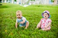 Two happy baby boy and a girl age 9 months old, sitting on the grass and interact, talk, look at each other. Royalty Free Stock Photo