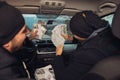 Two happy bank robbers celebrating their successful hit while sitting in the car they used for the robbery Royalty Free Stock Photo