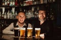 two happy bartenders at bar counter with glasses of beer Royalty Free Stock Photo