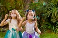 Two happy beautiful little girls playing with soap bubbles on a summer nature, one girl is wearing a blue ears tiger Royalty Free Stock Photo
