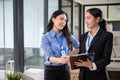 Two happy Asian businesswomen are having a discussion while standing in the office together Royalty Free Stock Photo