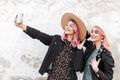 Two happy beautiful young stylish girls with pink hair in fashionable denim clothes with straw hats take a selfie photo near a Royalty Free Stock Photo