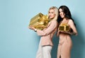 Two attractive girls holding gold gift boxes Royalty Free Stock Photo