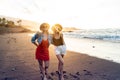 Two happy blonde caucasian women walking on the beach during beautiful sunset, smiling and having fun together. Romantic date. Royalty Free Stock Photo