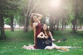 Two happy boho chic stylish girlfriends with guitar, picnic