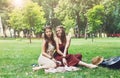 Two happy boho chic stylish girlfriends picnic in park