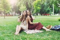 Two happy boho chic stylish girlfriends picnic in park