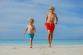 Two happy boys brothers big and small run on the sand beach Royalty Free Stock Photo