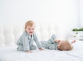 Two happy boys brothers laying on white bed in pajamas, having fun together, laughing, playing Royalty Free Stock Photo