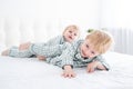 Two happy boys brothers laying on white bed in pajamas, having fun together, laughing, playing Royalty Free Stock Photo