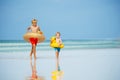 Two happy boys run with inflatable buoys doughnut and duck Royalty Free Stock Photo