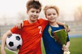 Two happy boys soccer players holding soccer ball and golden trophy