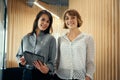 Two happy business women looking at camera with digital tablet during meeting in office Royalty Free Stock Photo