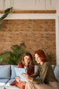 Two busy happy business women using tablet working sitting in office. Vertical. Royalty Free Stock Photo