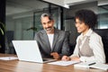 Two happy busy diverse business people talking using laptop working in office. Royalty Free Stock Photo