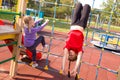 Two happy caucasian girls having fun on playground, climbing the rope net