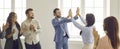 Two happy business people give each other a high five while coworkers are applauding Royalty Free Stock Photo