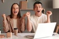 Two happy cheerful Caucasian businesspeople showing clenched fist, looking at camera while sitting in front of laptop screen, Royalty Free Stock Photo