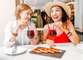 Happy cheerful girl friends drinking wine and having lunch at seafood restaurant Royalty Free Stock Photo