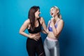 Two happy and cheerful girls dressed in fitness bodysuits, best friends having fun. Royalty Free Stock Photo