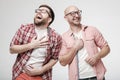Two happy, cheerful men in glasses laugh out loud, opening their mouths wide and closing their eyes. Positive emotions. Royalty Free Stock Photo