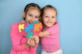 Two happy cheerful sisters show symbol of autism with image of colored puzzles