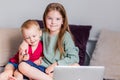 Two happy children a boy and a girl lie on a sofa in home clothes and watch video on a laptop Royalty Free Stock Photo