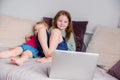 Two happy children a boy and a girl lie on a sofa in home clothes and watch video on a laptop Royalty Free Stock Photo