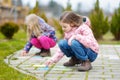 Two happy children drawing with colorful chalks on a sidewalk. Summer activity for small kids. Royalty Free Stock Photo