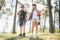 Two happy children having fun during forest hike on beautiful day in pine forest. Cute boy scout with binoculars during Royalty Free Stock Photo