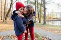 Two happy children hugging and kissing in autumn park. Close up sunny lifestyle fashion portrait of two beautiful caucasian girls Royalty Free Stock Photo