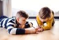 Two happy children lying on floor indoors at home, drawing. Royalty Free Stock Photo