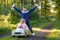 Two happy children playing with big old toy car in autumn forest, outdoors. Kid boy pushing and driving car with little Royalty Free Stock Photo