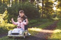 Two happy children playing with big old toy car in autumn forest, outdoors. Kid boy pushing and driving car with little Royalty Free Stock Photo