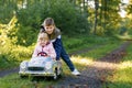 Two happy children playing with big old toy car in autumn forest, outdoors. Kid boy pushing and driving car with little Royalty Free Stock Photo