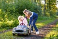 Two happy children playing with big old toy car in autumn forest, outdoors. Kid boy pushing and driving car with little Royalty Free Stock Photo