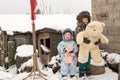 Two happy children in winter fashion clothes posing with a toy pig and a bear in the courtyard of a village house. First snow, fam Royalty Free Stock Photo