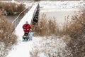 Two happy children in winter fashion clothes ride a sleigh with a toy pig and a bear on a bridge across the river. First snow, fam Royalty Free Stock Photo